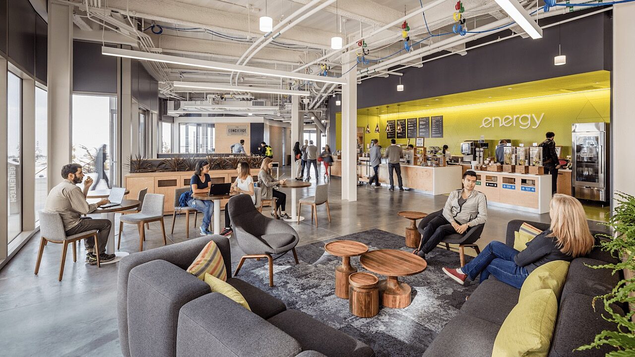 interior office environment with people sitting in communal area working and having conversations with others