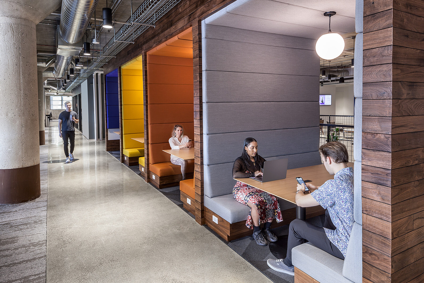 Office with booths and people sitting in the booths together and working and talking