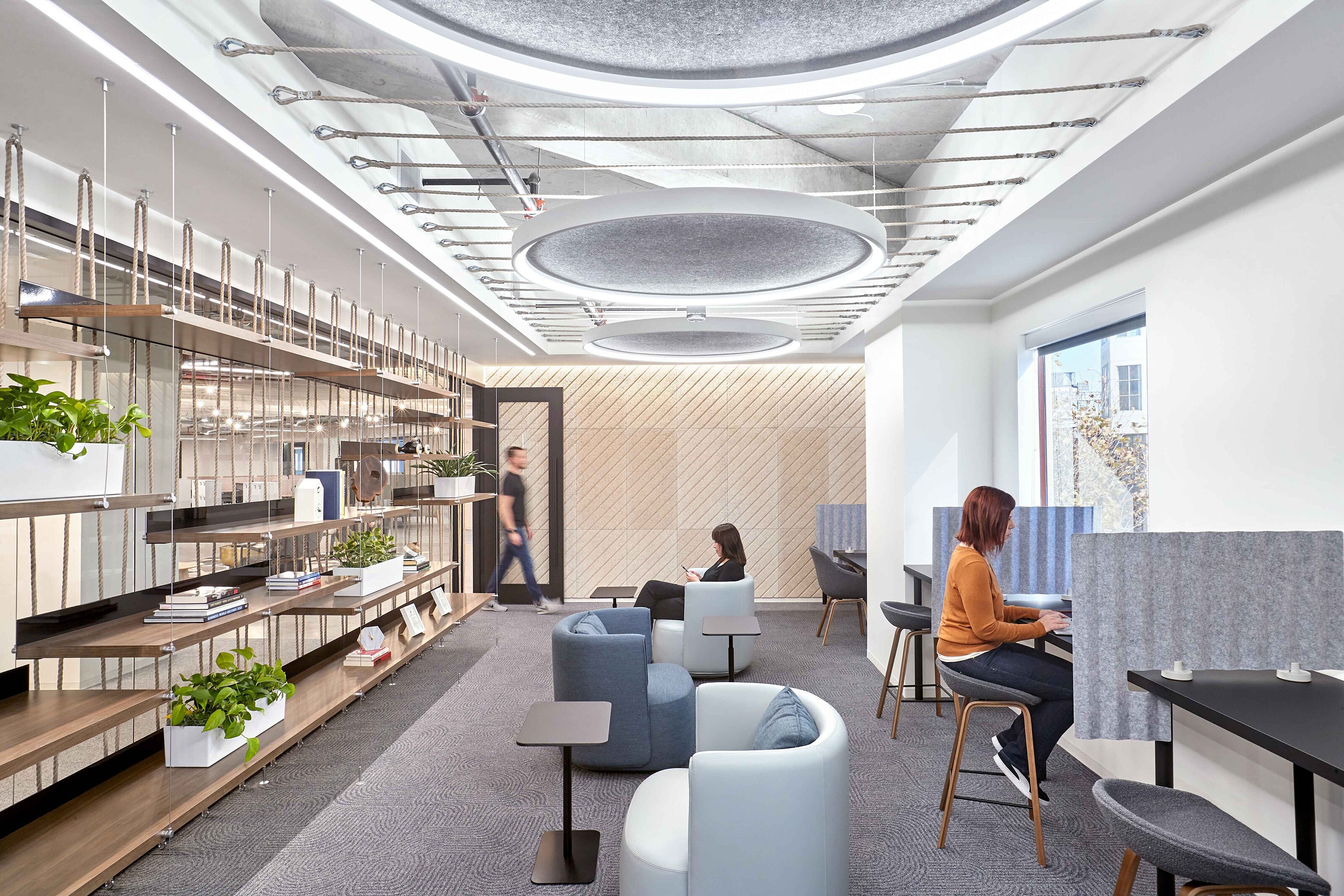 interior space with 2 women sitting separately looking at their computer and phone
