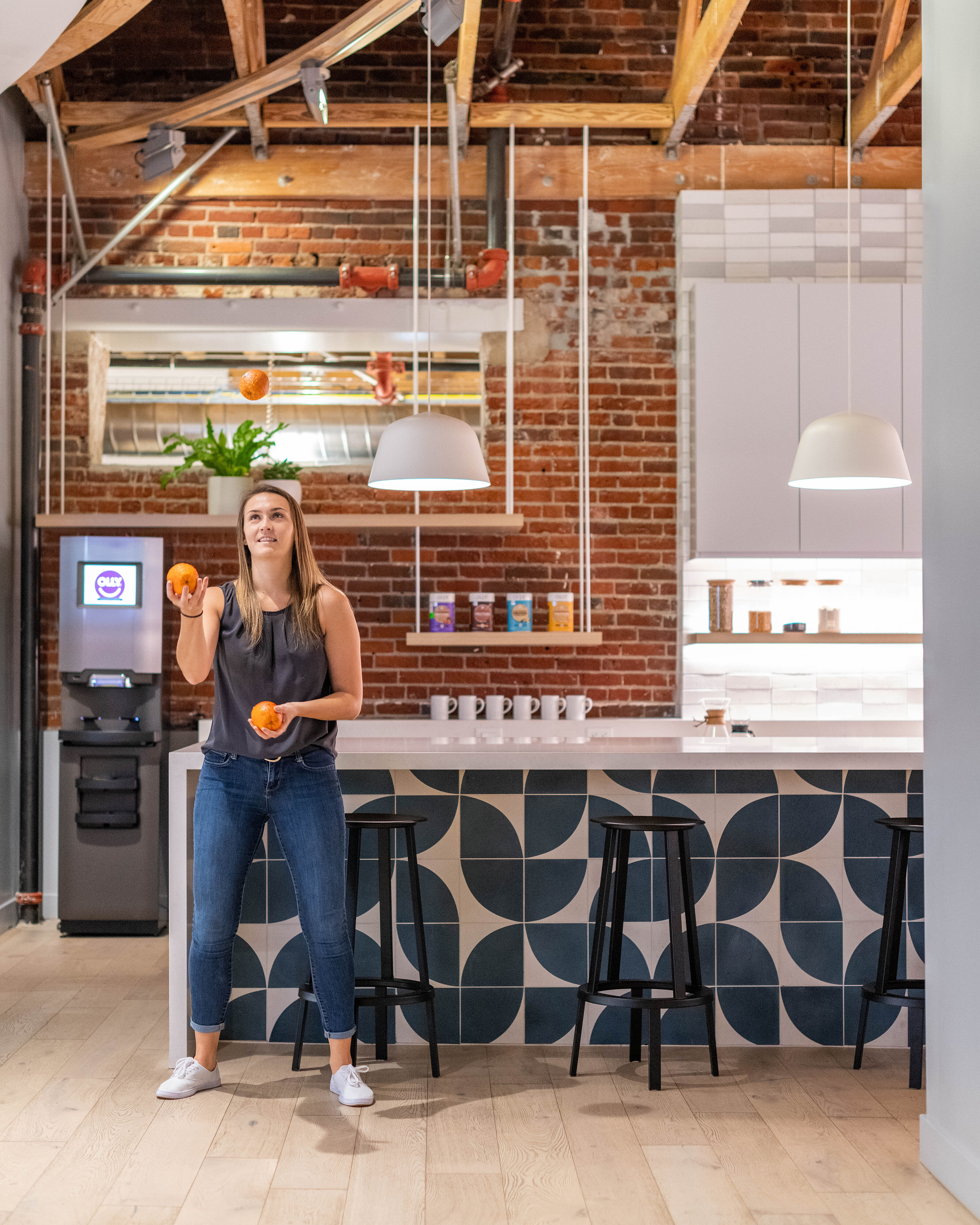 Lady juggling oranges in open kitchen area of modern office space